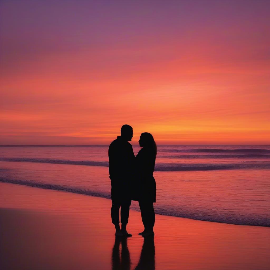 Couple on the beach at sunset, embracing while looking at the sun.